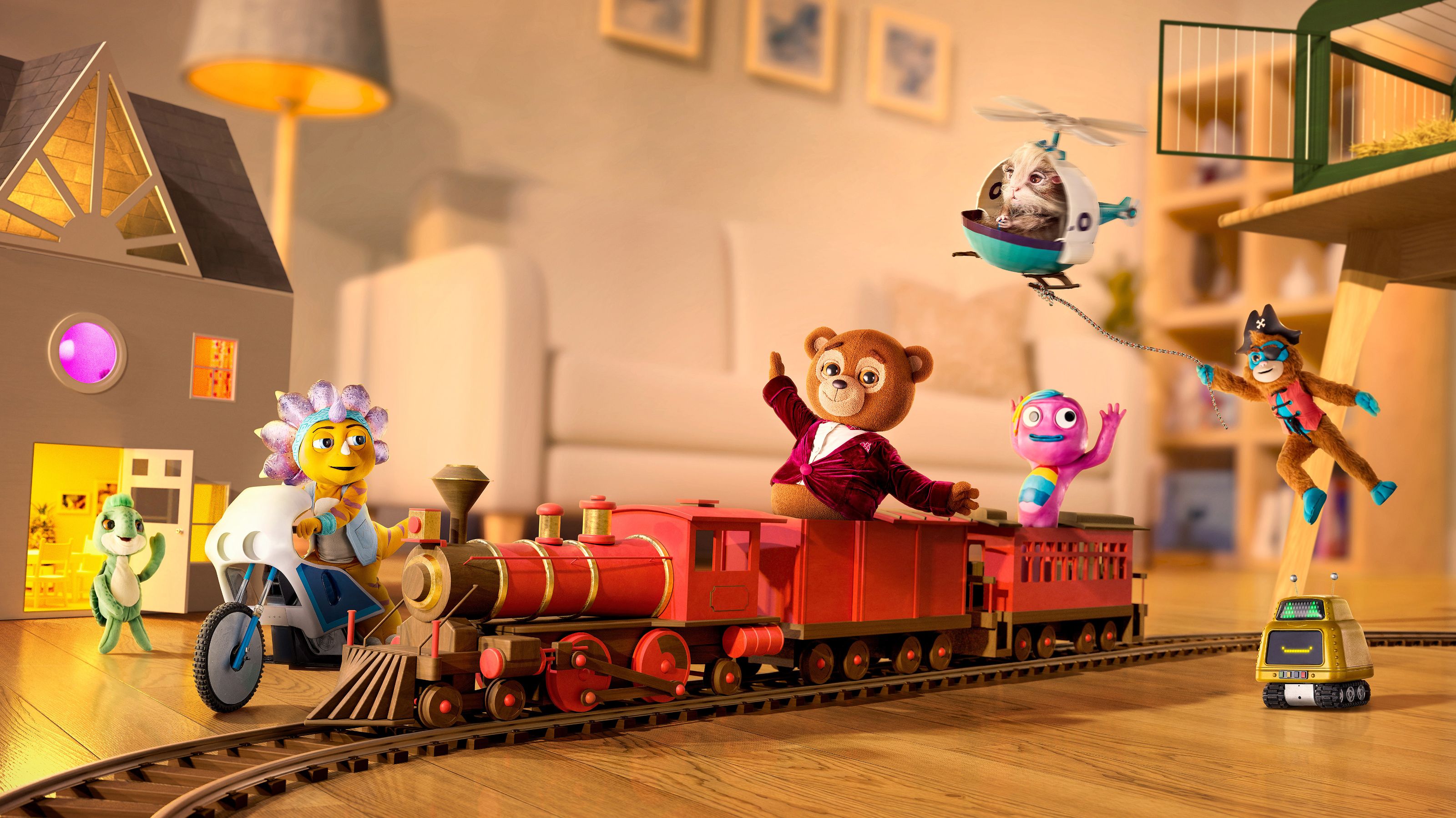 A colorful scene features playful toy characters and a miniature train set on a wooden floor. Among them are a bear in a red jacket, a flower character on a bike, a purple figure waving, and a toy pirate with a robotic companion, all positioned around a whimsical toy house. A small helicopter hovers above, carrying an animal.